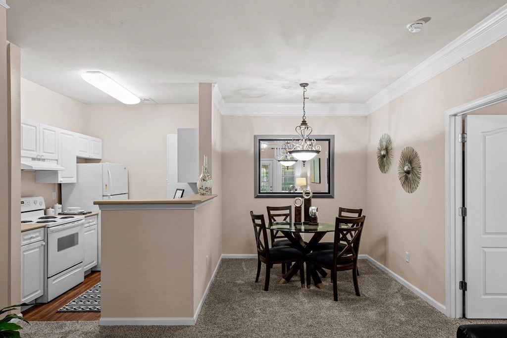 a dining area with a table and chairs and a kitchen in the background at Creekside, Overland Park, Kansas