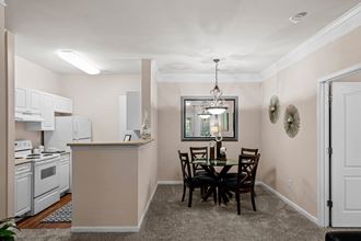 a dining area with a table and chairs and a kitchen in the background a dining area with a table and chairs and a kitchen in the background at Creekside, Overland Park, Kansas