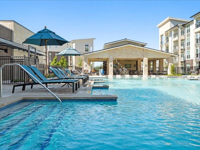 a swimming pool with chairs and umbrellas next to a building