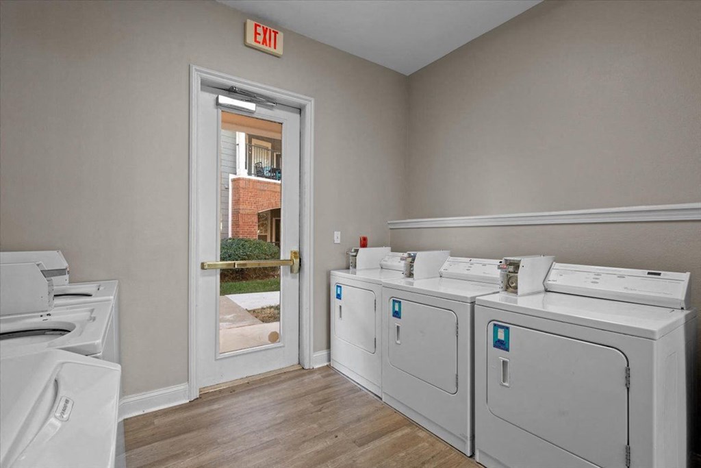 A laundry room with a washer and dryer on the right and a door leading outside. at Somerset Oaks Apartment Homes, Kansas