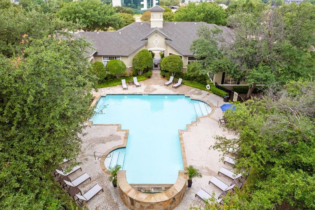 a swimming pool with lounge chairs and trees in the background