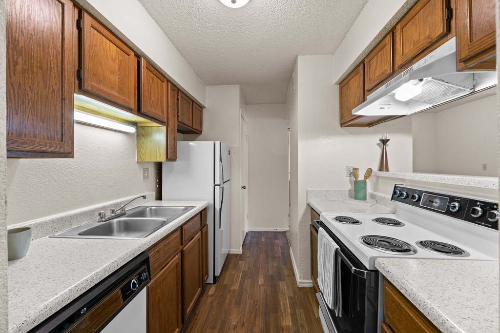 A kitchen with wooden cabinets and a white stove top oven. at Coventry Oaks Apartments, Kansas, 66214