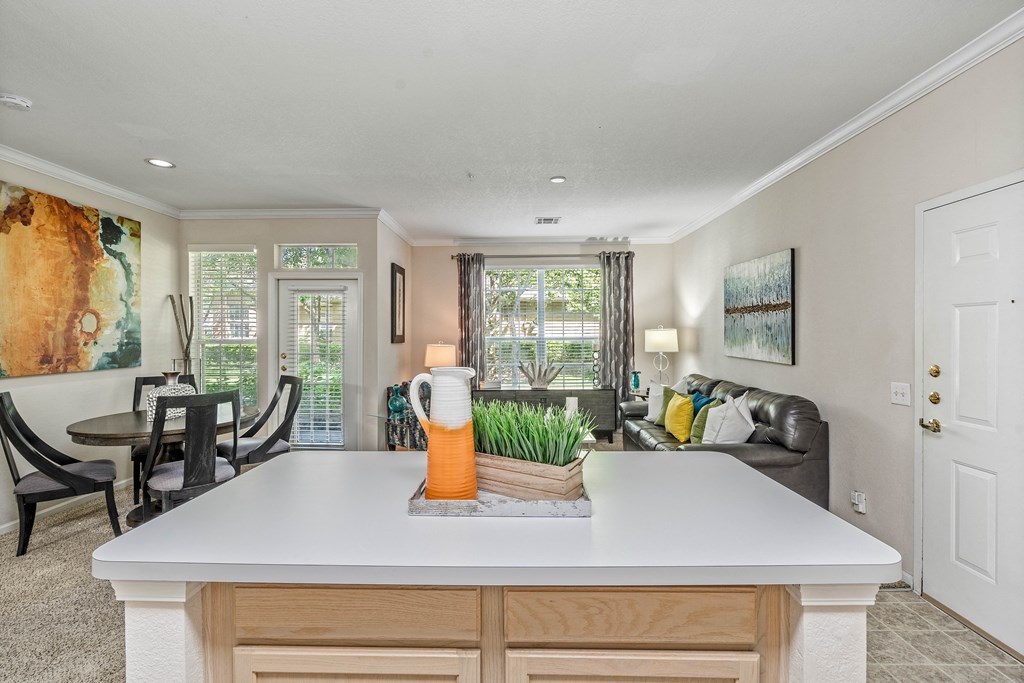 a kitchen with a center island next to a living room with a couch and a table