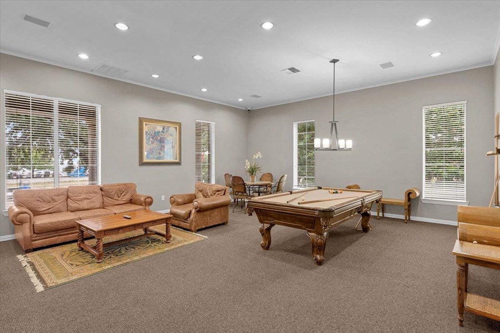a game room with a pool table and couches at The Clairborne Apartment Homes, Grand Prairie, TX