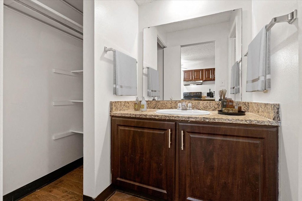 a bathroom with a sink and a mirror and a refrigerator at Malvern Hill Apartment Homes, 66103 66214
