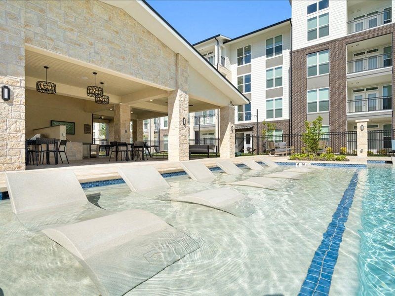 a swimming pool with white lounge chairs in front of a building