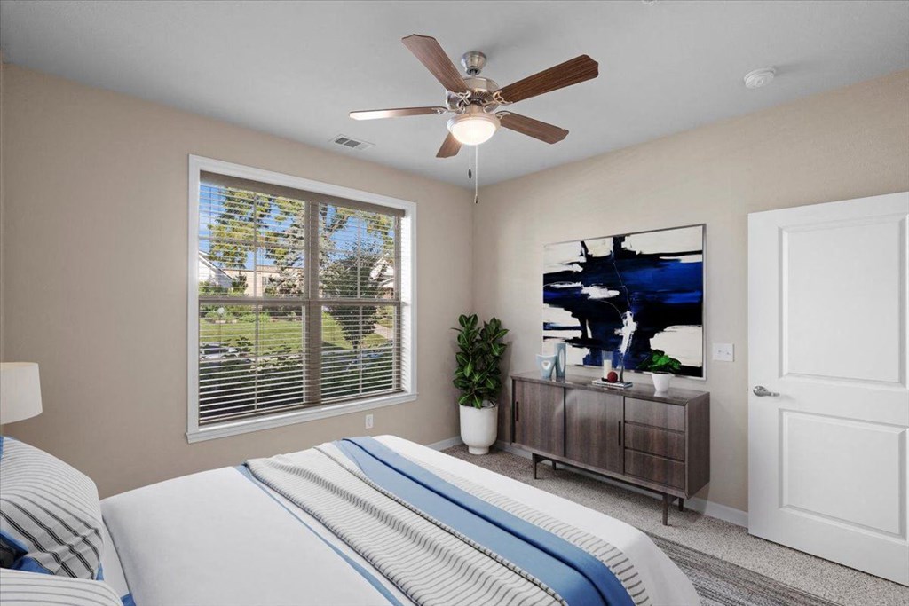 a bedroom with a large window and a ceiling fan