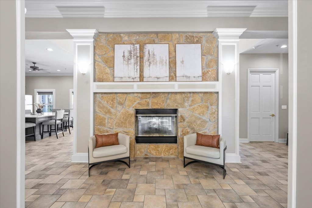 A living room with a stone fireplace and two chairs. at Somerset Oaks Apartment Homes, Olathe