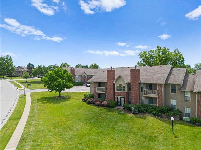 an apartment building with a green lawn and trees at Highland Park Apartment Homes, Kansas, 66214