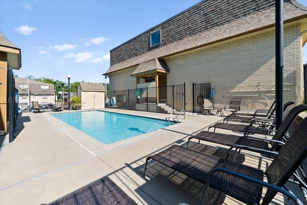 A pool area with lounge chairs and a building in the background. at Malvern Hill Apartment Homes, 66103, KS