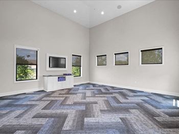 an empty living room with a tv and windows