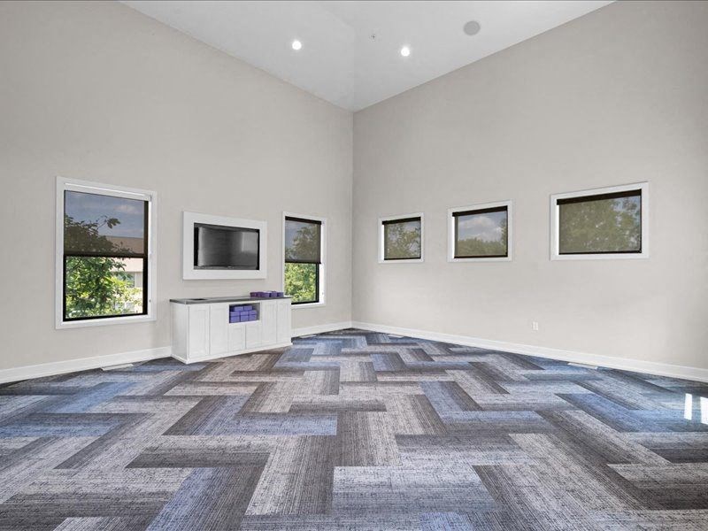 an empty living room with a tv and windows