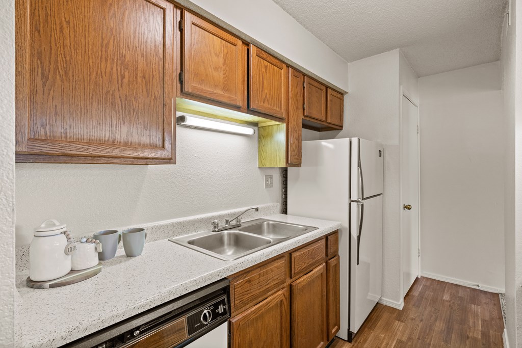 A kitchen with wooden cabinets and a white refrigerator. at Coventry Oaks Apartments, Overland Park, KS