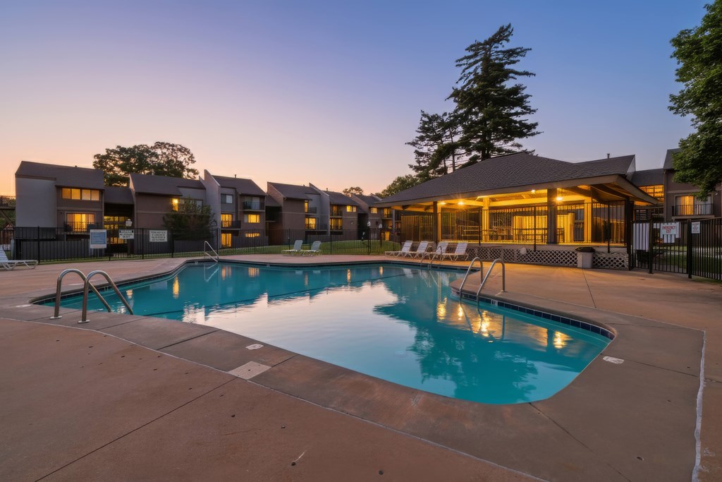 A large outdoor swimming pool surrounded by lounge chairs and a building in the background.