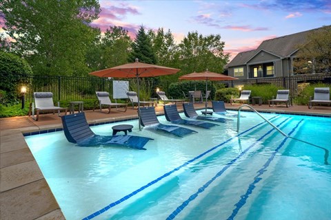 A pool with blue water and lounge chairs.
