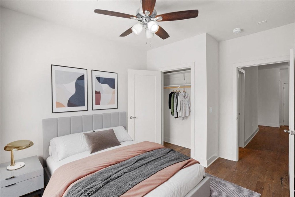 A bedroom with a ceiling fan, clothes closet, and hardwood floors at Mirabelle Luxury Apartments, Kansas City, MO, 64111