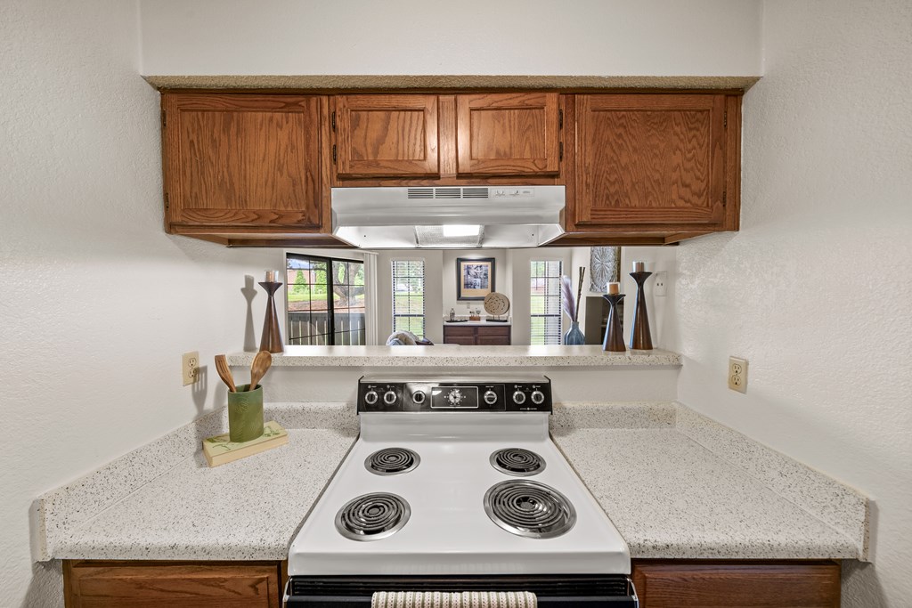 A kitchen with a stove top oven and wooden cabinets. at Coventry Oaks Apartments, Overland Park