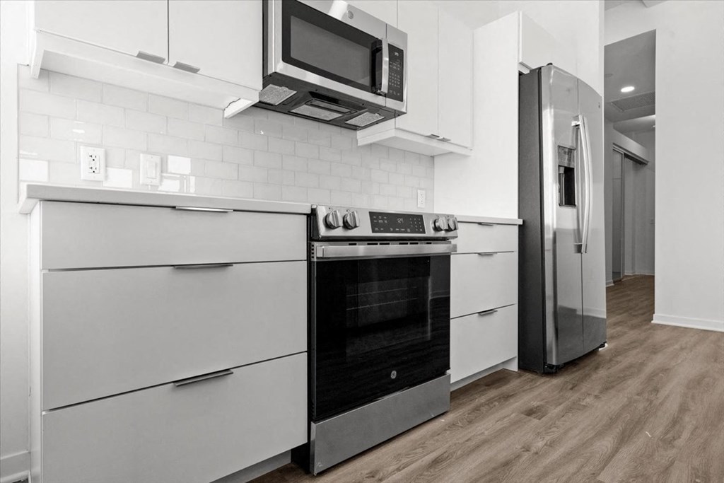 a kitchen with white cabinets and a stove and a refrigerator at Sky On Main Apartments, Missouri City 64105