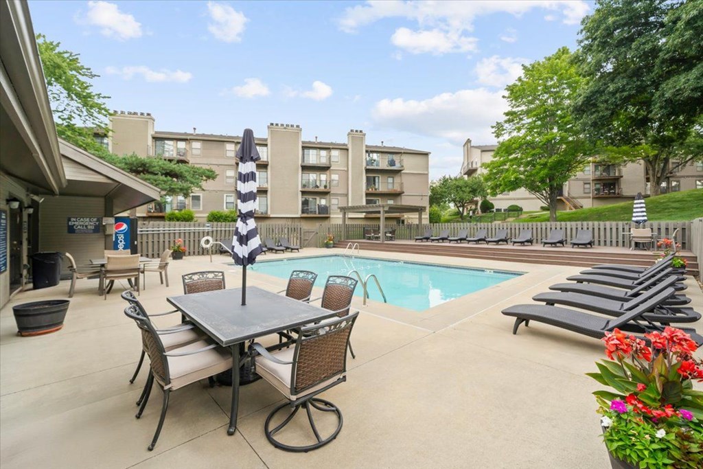 A pool area with a table and chairs and a striped umbrella.