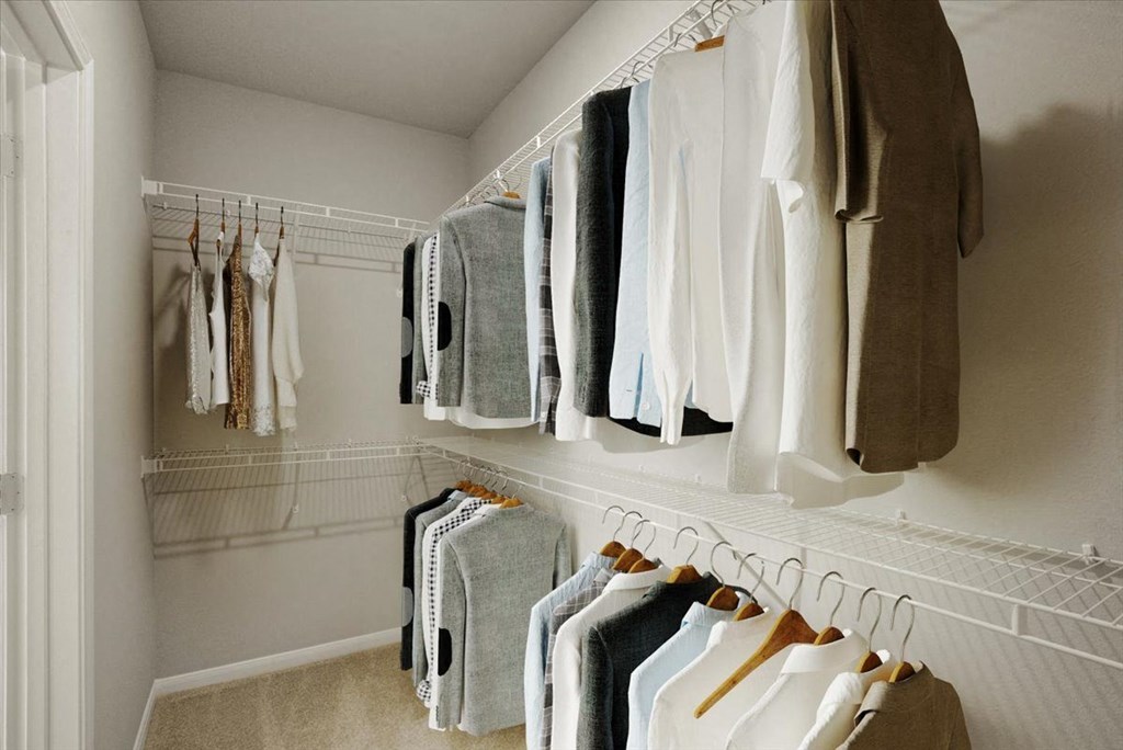 a walk in closet with a rack of clothes