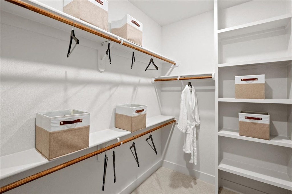 a walk in closet with white shelves and baskets