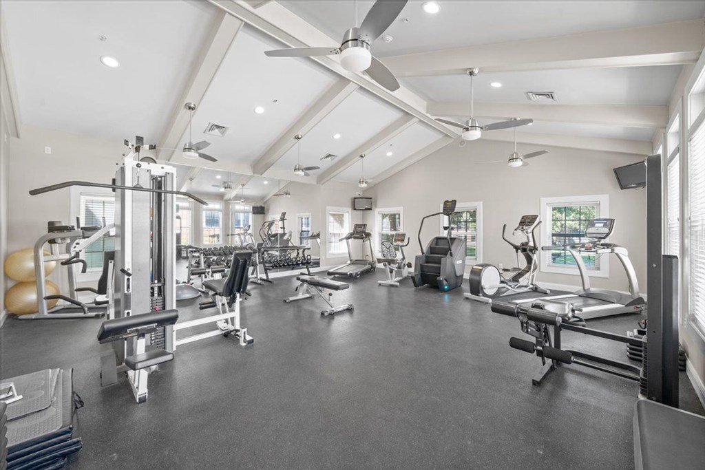 A spacious gym with various exercise equipment and a ceiling fan. at Somerset Oaks Apartment Homes, Kansas