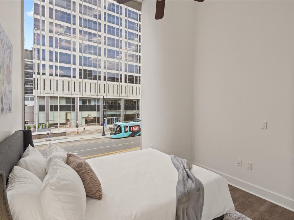a bedroom with a large bed in front of a window at Sky On Main Apartments, Missouri City 64105