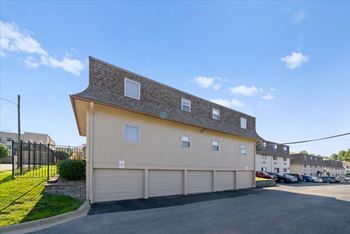 A two-story building with a garage door and a driveway in front. at Malvern Hill Apartment Homes, Kansas, 66214