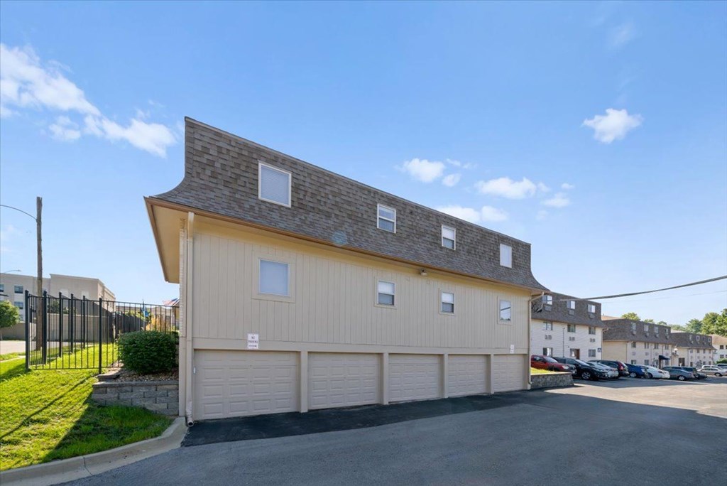 A two-story building with a garage door and a driveway in front. at Malvern Hill Apartment Homes, 66103 66214