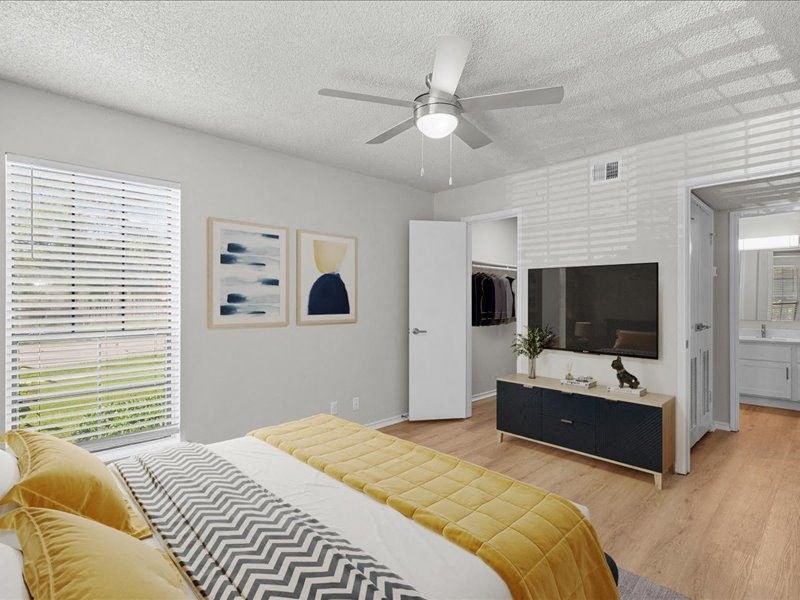 a bedroom with a bed and a tv a bedroom with a bed and a tv at Highland Park Apartment Homes, Overland Park