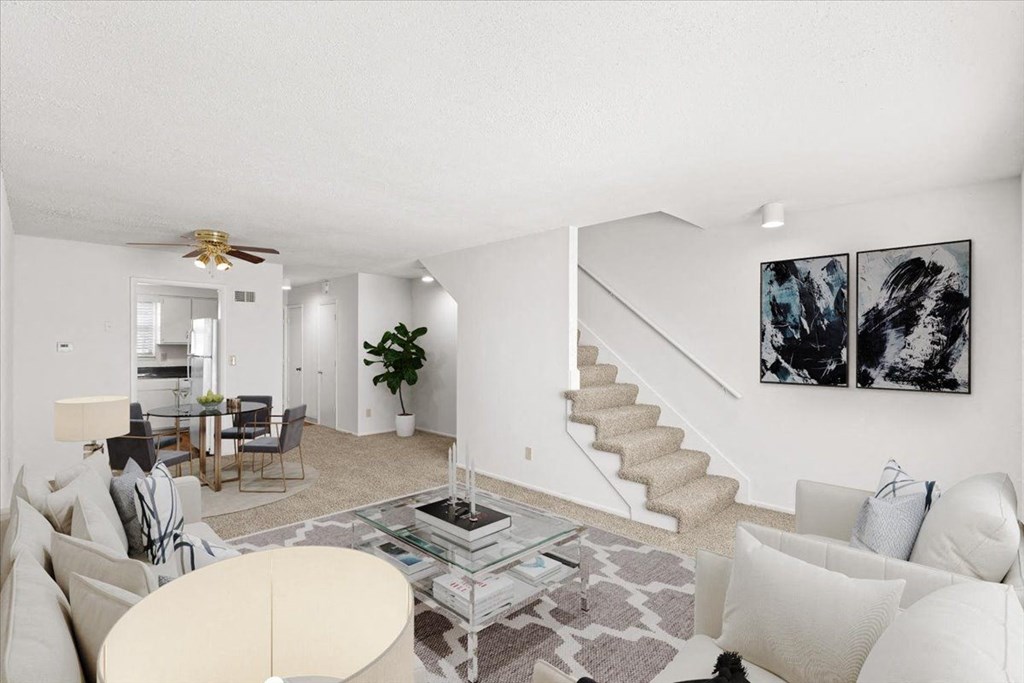 a living room with couches and a table and a staircase