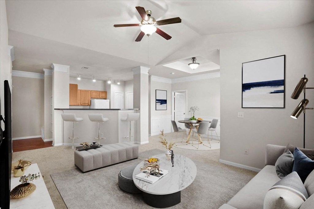 an open living room with a kitchen and a ceiling fan