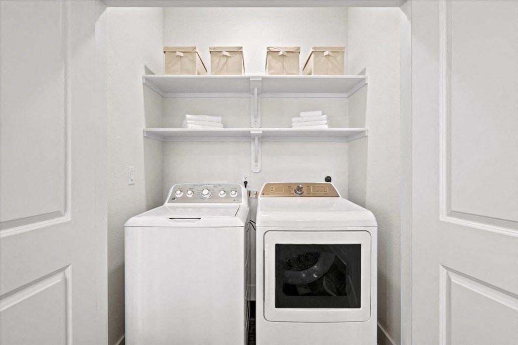 a white laundry room with two washes and a dryer