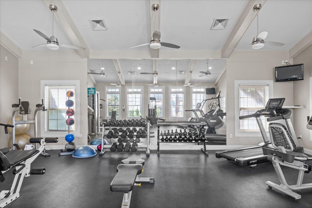 A spacious gym with a variety of equipment including treadmills, weights, and a television. at Somerset Oaks Apartment Homes, Olathe, KS, 66062
