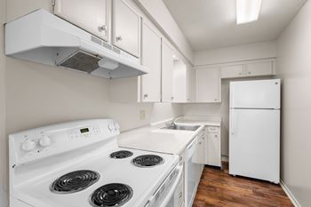 A fully equipped kitchen with white appliances including a dishwasher, oven, stove & refrigerator.