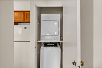A white washing machine is in a small laundry room. at Coventry Oaks Apartments, Kansas