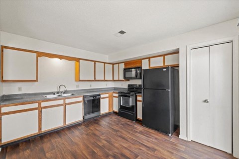 a kitchen with white cabinets and a black refrigerator at Deerfield Apartments, Olathe, KS