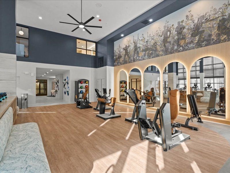 a gym with weights and cardio equipment and a painting on the wall