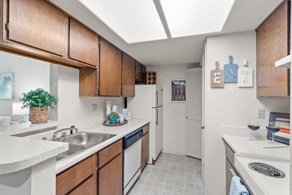 a kitchen with white appliances and wooden cabinets at Pebblebrook, Overland Park