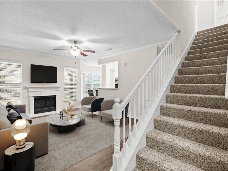 a living room with a staircase and a ceiling fan