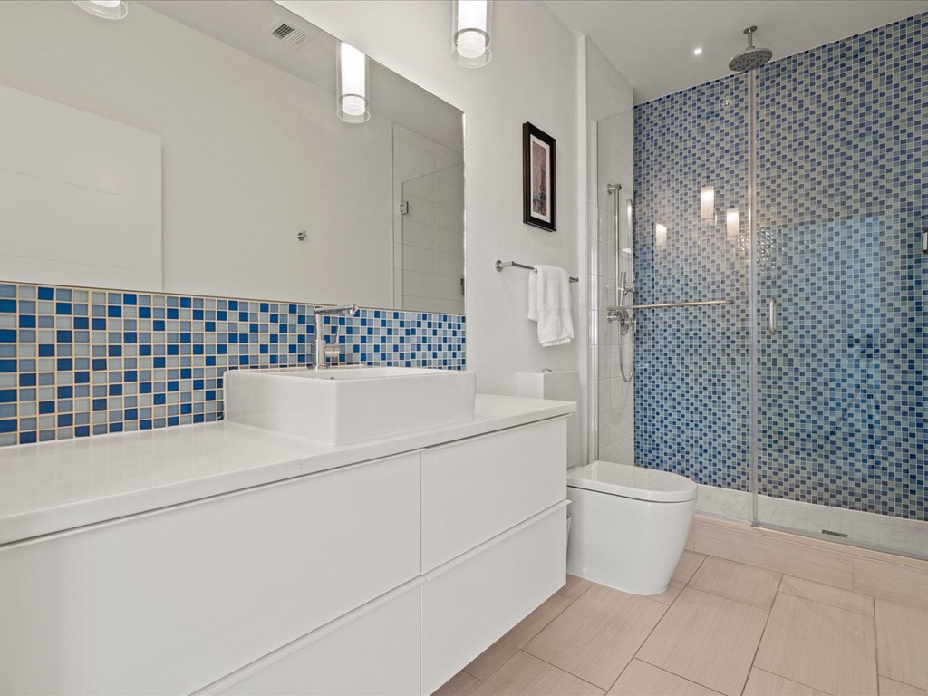 a bathroom with a blue and white tiled wall at Sky On Main Apartments, Missouri City, MO