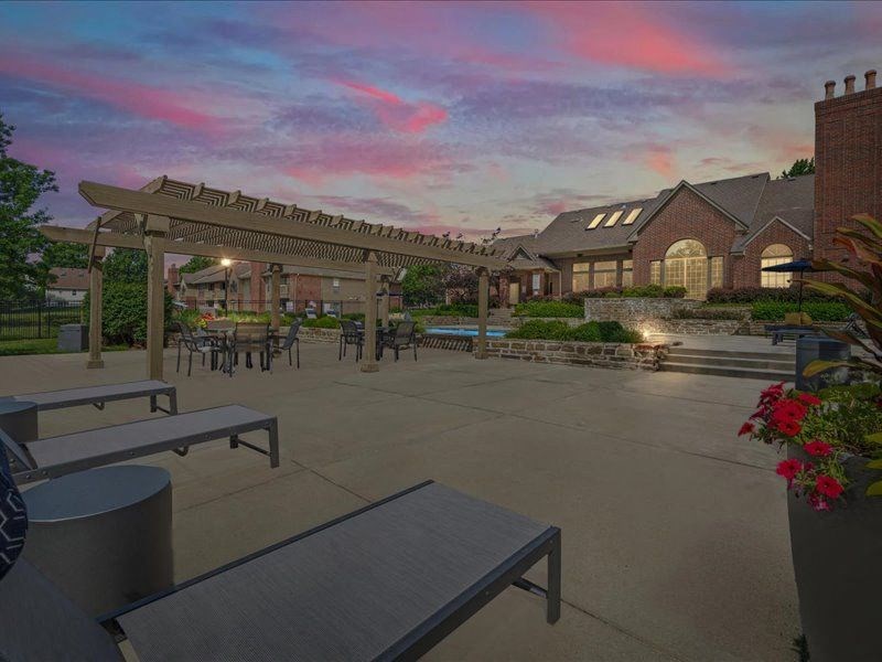 a patio with benches and tables in front of a building at Highland Park Apartment Homes, Kansas, 66214