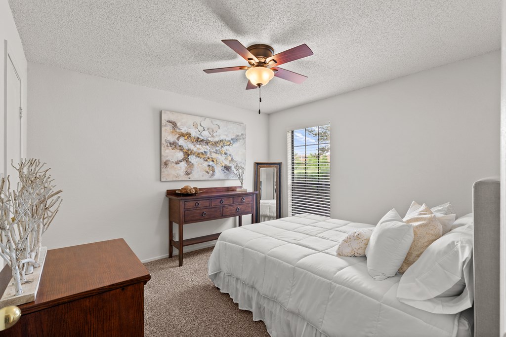 A bedroom with a bed, dresser, and a ceiling fan. at Coventry Oaks Apartments, Overland Park, Kansas