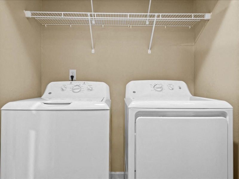 two washers and dryers in a laundry room with a rack on the wall