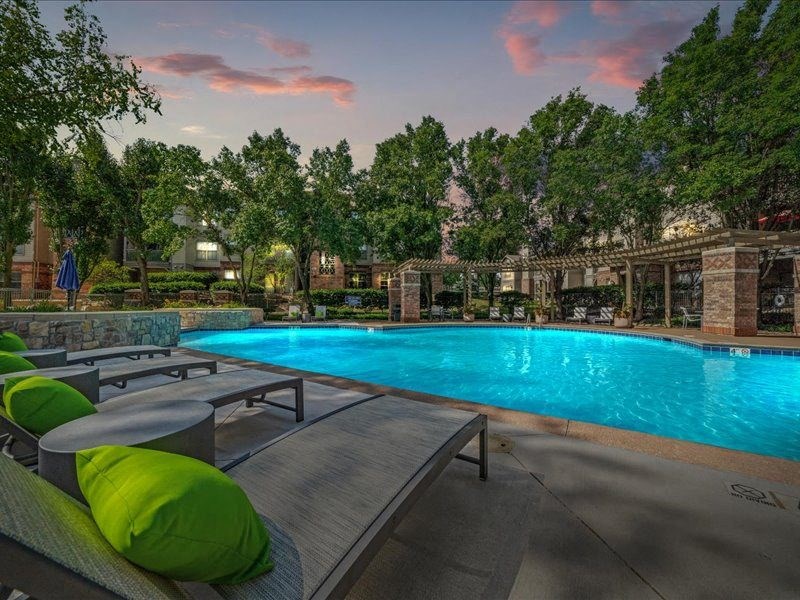 a swimming pool with chairs and tables next to it