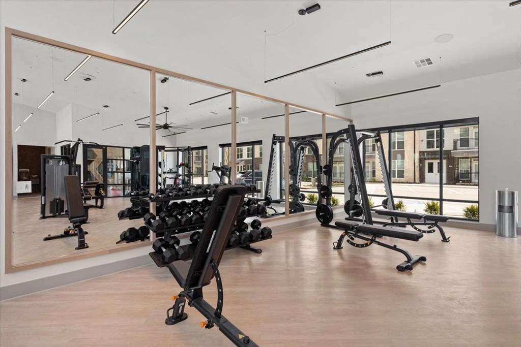 a gym with weights and mirrors in a development with condos