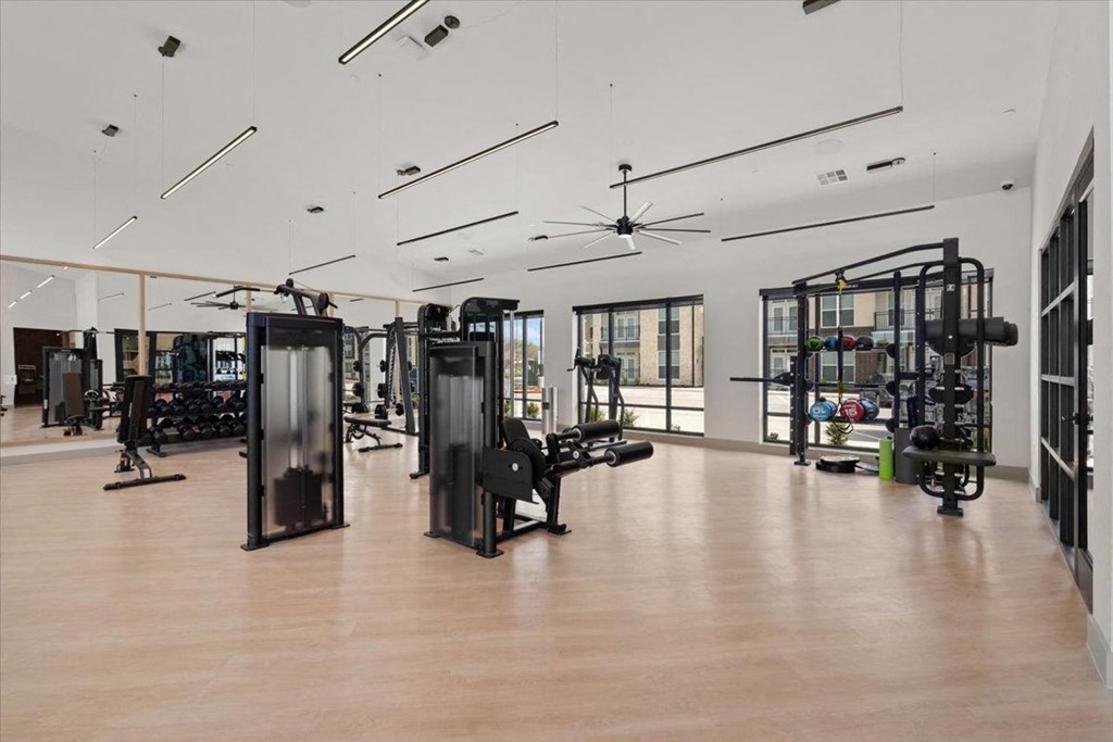 the gym has weights and other exercise equipment in a large room with windows