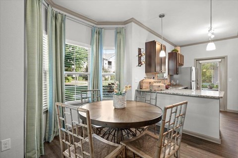 a dining room with a table and chairs and a kitchen in the background at Stonepost Crossing Apartments, Overland Park, KS, 66213