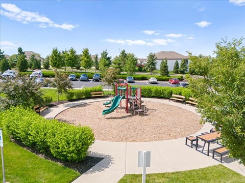 A playground with a green slide and a red swing set.