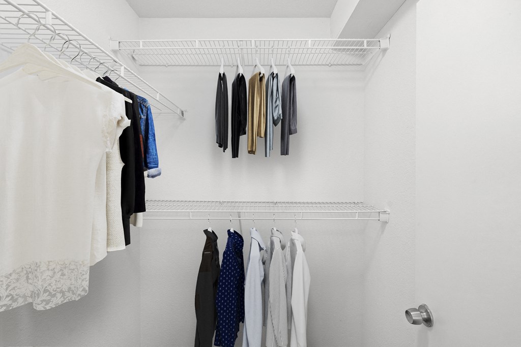 a walk in closet with white walls and a white metal shelf with clothes on it at Malvern Hill Apartment Homes, 66103, Kansas